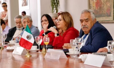 Lucy Meza sentada en una mesa en una reunión con empresarios.