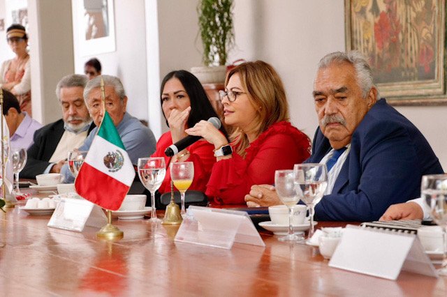 Lucy Meza sentada en una mesa en una reunión con empresarios.