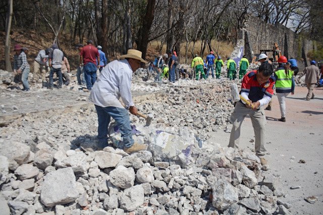 Trabajadores picando piedra para retirar escombros en Río Mayo