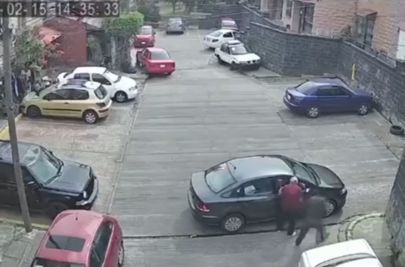 Auto estacionado en calle de Lomas de Ahuatlán con dos sujetos asaltando
