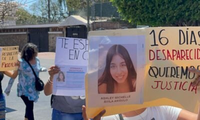 Cartulina con el rostro de una menor desaparecida y personas que caminan por la calle