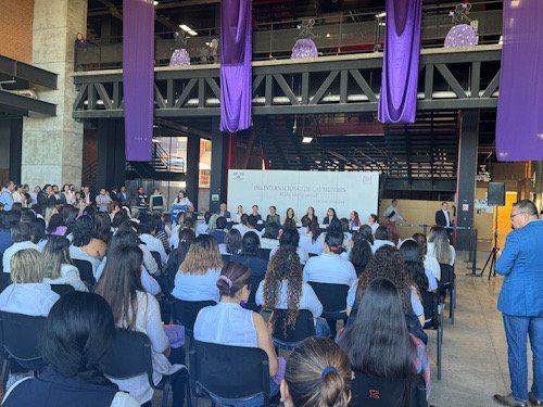 Autoridades universitarias sentadas en una mesa, con muchas mujeres de invitadas