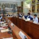 Varias personas levantando la mano para aprobar algo en un cuerpo con varios cuadros