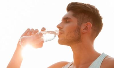 Joven con una botella de agua y sol de fondo