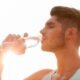 Joven con una botella de agua y sol de fondo