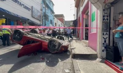 Auto color rojo, volcado completamente en una calle