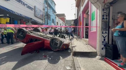 Auto color rojo, volcado completamente en una calle