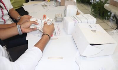 Mujer en una mesa en las manos varias credenciales de elector