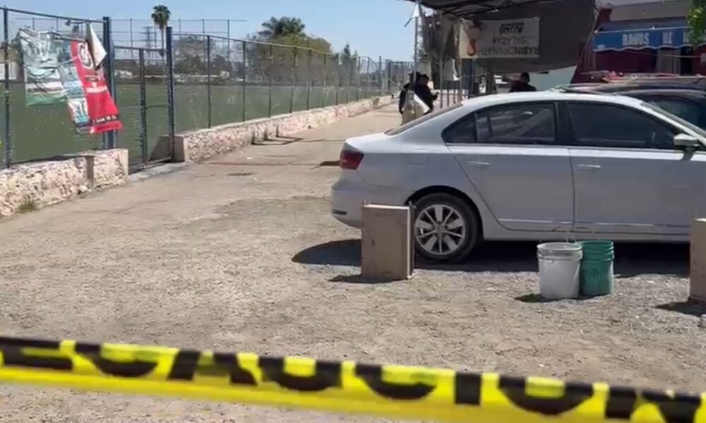 Cancha de fútbol, un auto blanco y una cinta acordonando la zona