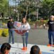 Mujer con tenis naranjas y blusa blanca, acompañada de dos hombres más con los logos de Movimiento Ciudadano