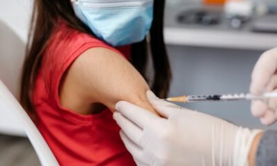 Una niña con blusa roja, descubierto el brazo y una jeringa