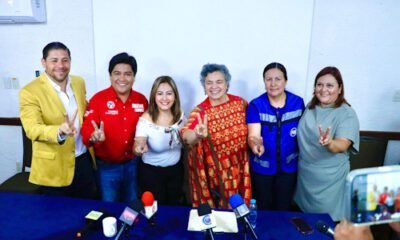 4 mujeres y dos hombres mostrando dos dedos