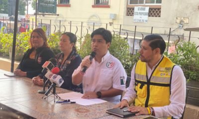 Personas sentadas en una mesa con micrófonos en una conferencia