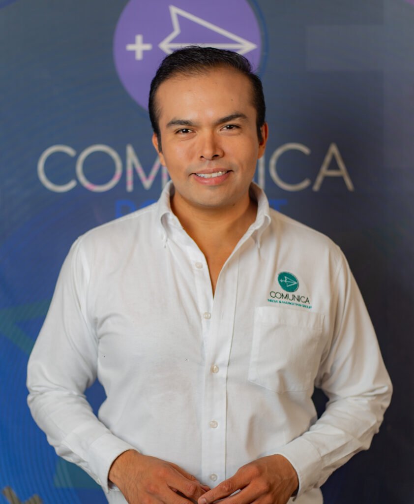 hombre con camisa blanca sonriente, productor, conductor y creativo de comunica mas media